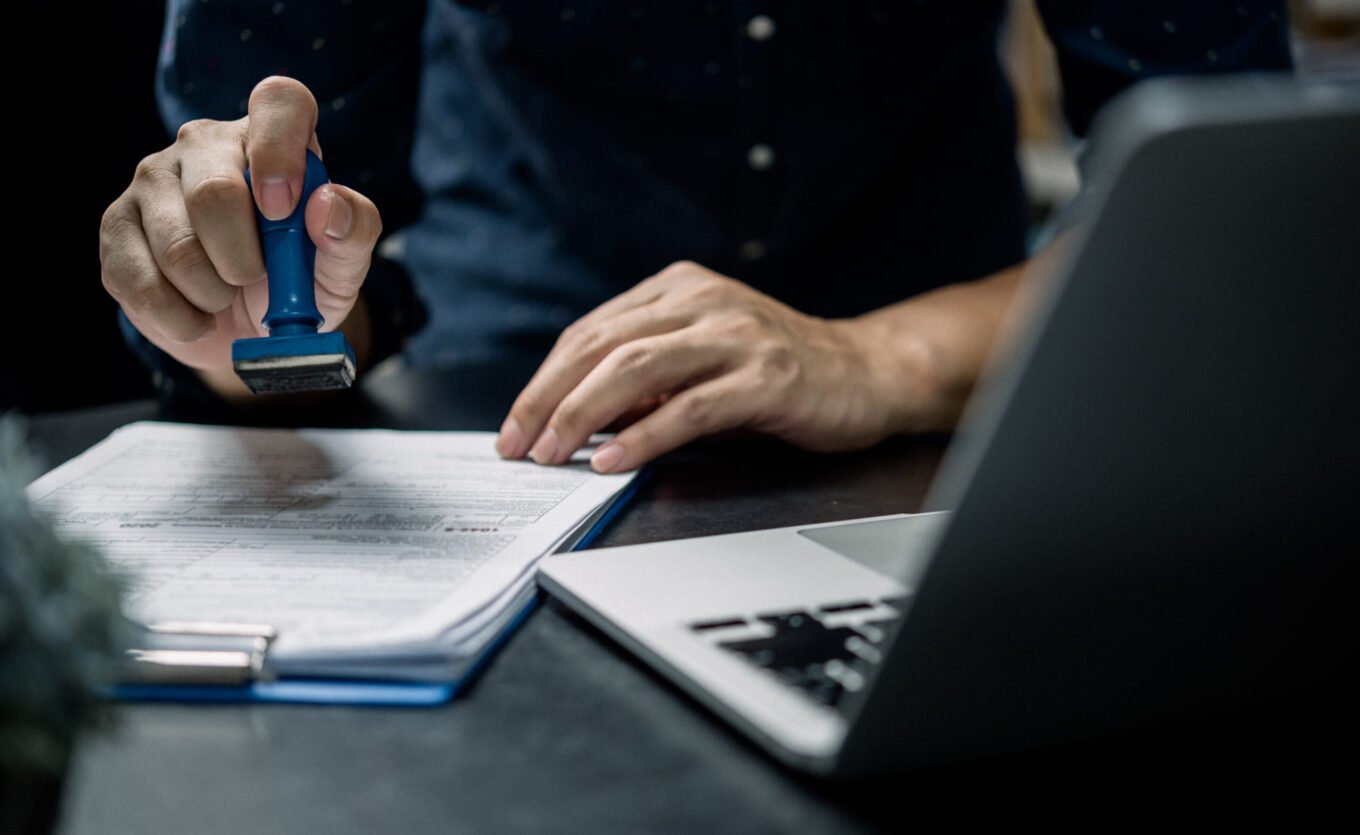 Visa Assessment Man stamping approval of work finance banking or investment marketing documents on desk.